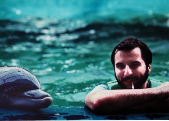 El gran maestro Randall Brill posa en esta foto de alrededor de la década de 1980 con uno de los delfines que ayudó a entrenar en el zoológico de Brookfield. El Gran Maestro Randall Brill pasó a desarrollar tecnologías de sonar con la Marina.